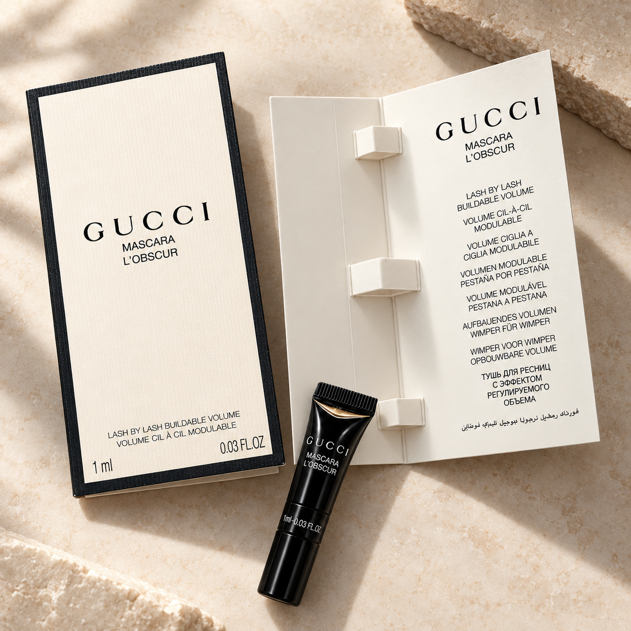 Gucci Mascara L'Obscur tube with open booklet on marble surface